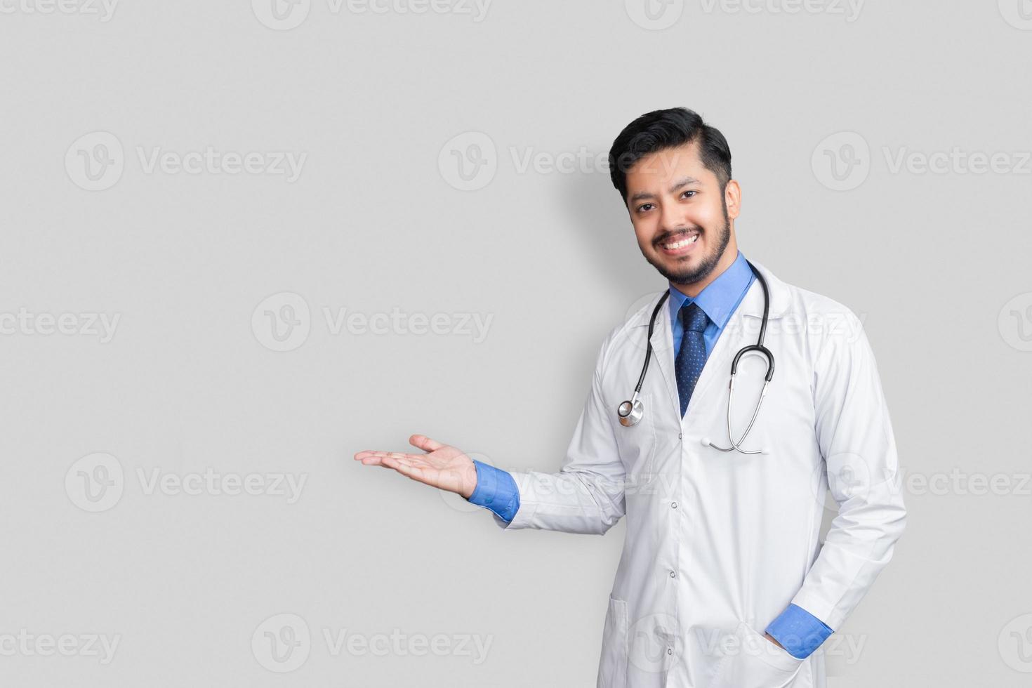 médico vestindo uniforme sorrindo enquanto apresenta e aponta isolado com espaço de cópia foto