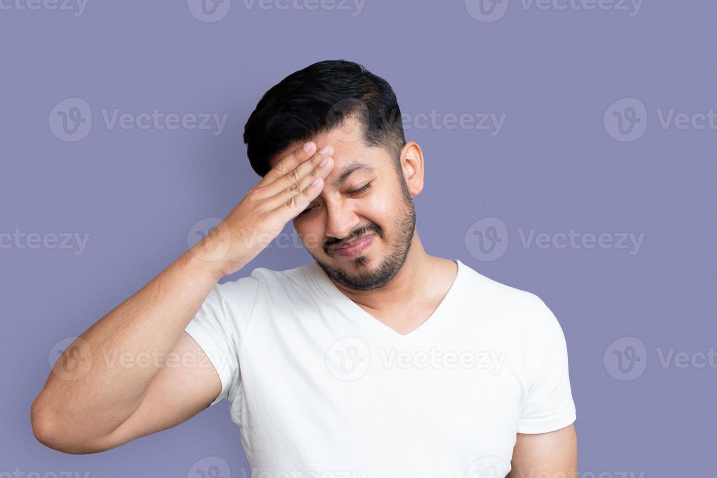 Feche a foto da aparência perfeita do homem jovem, um braço, a mão na testa. terrível dor de cabeça, dor de cabeça, fechado usar camiseta branca casual isolada no fundo