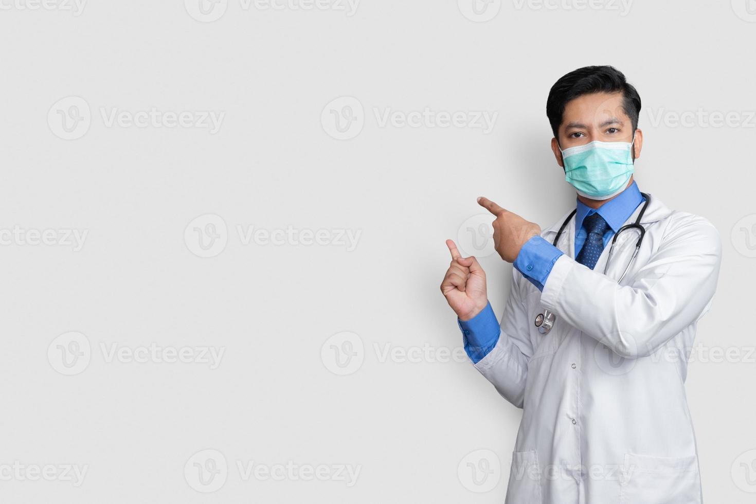 médico vestindo uniforme sorrindo enquanto apresenta e aponta isolado no fundo branco com espaço de cópia foto