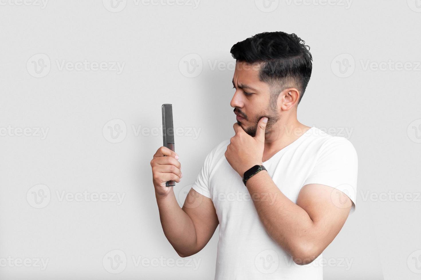 retrato de close-up de aparência perfeita incrível jovem segurando um pente na mão isolado sobre fundo branco foto