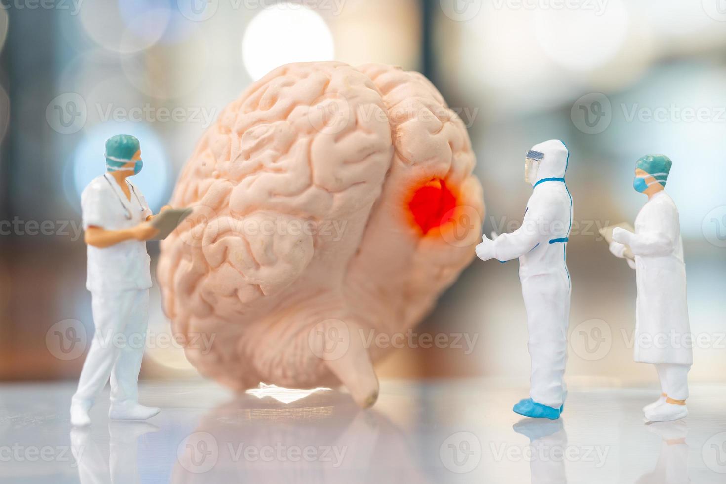 pessoas em miniatura, médico e enfermeira, observando e discutindo sobre o cérebro humano foto