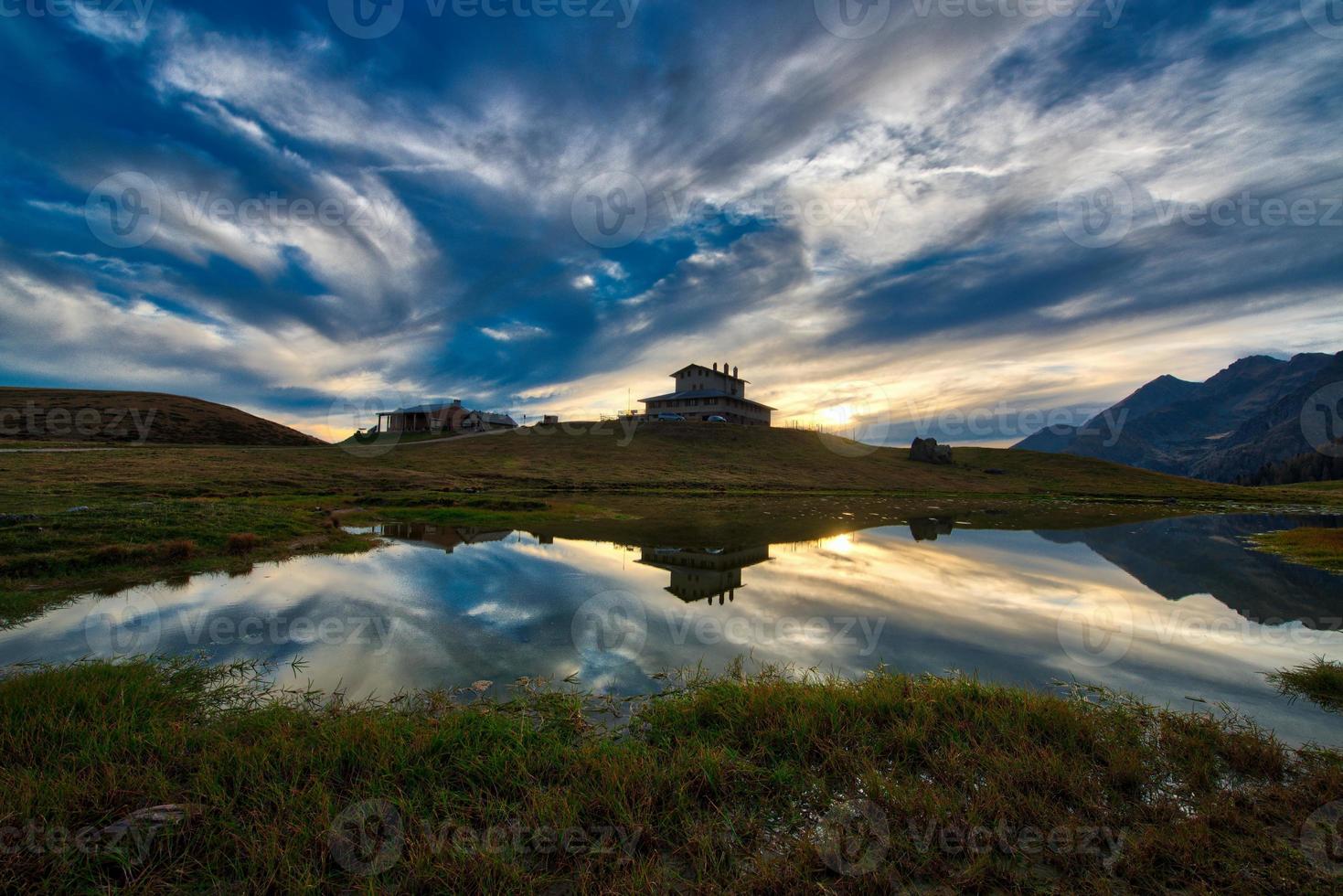 paisagem montanhosa ao pôr do sol perto de uma cabana alpina foto