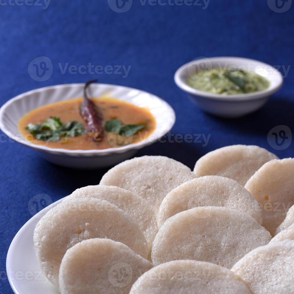 idli com sambar e chutney de coco no fundo azul, prato indiano comida favorita do sul da Índia rava idli ou semolina à toa ou rava à toa, servido com sambar e chutney verde. foto