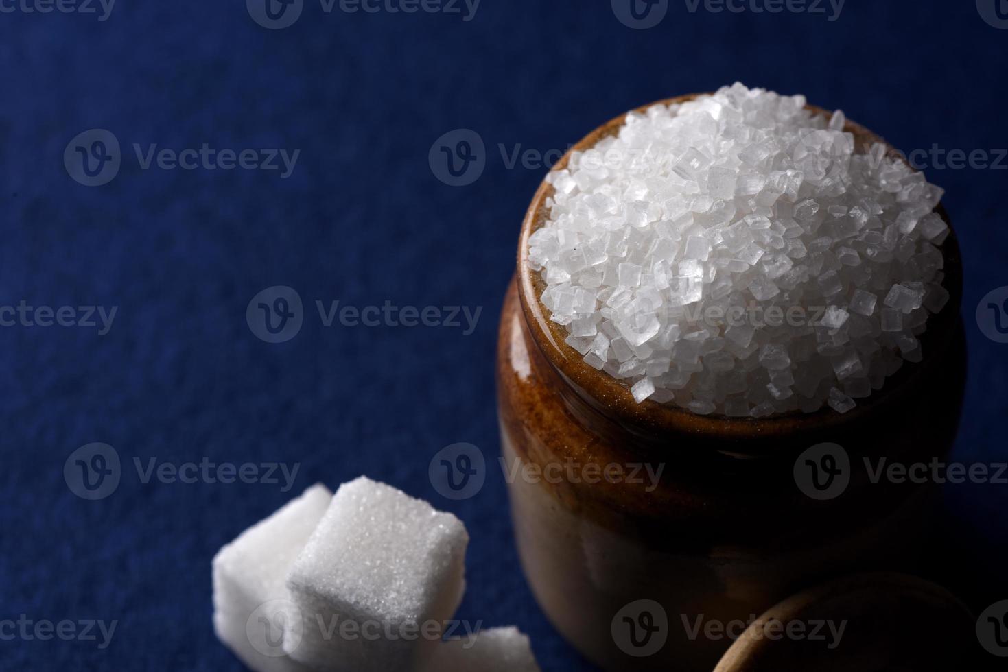 açúcar. açúcar granulado branco e açúcar refinado em um fundo azul foto