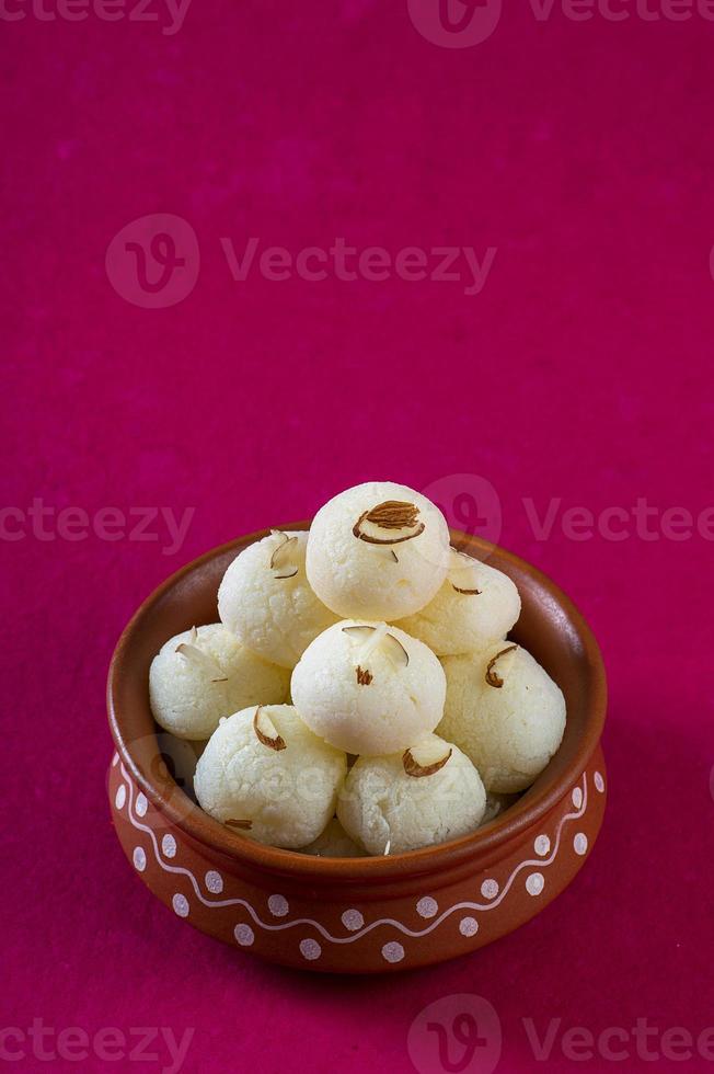 doce indiano ou sobremesa - rasgulla, famoso doce bengali em tigela de barro em um fundo rosa. foto