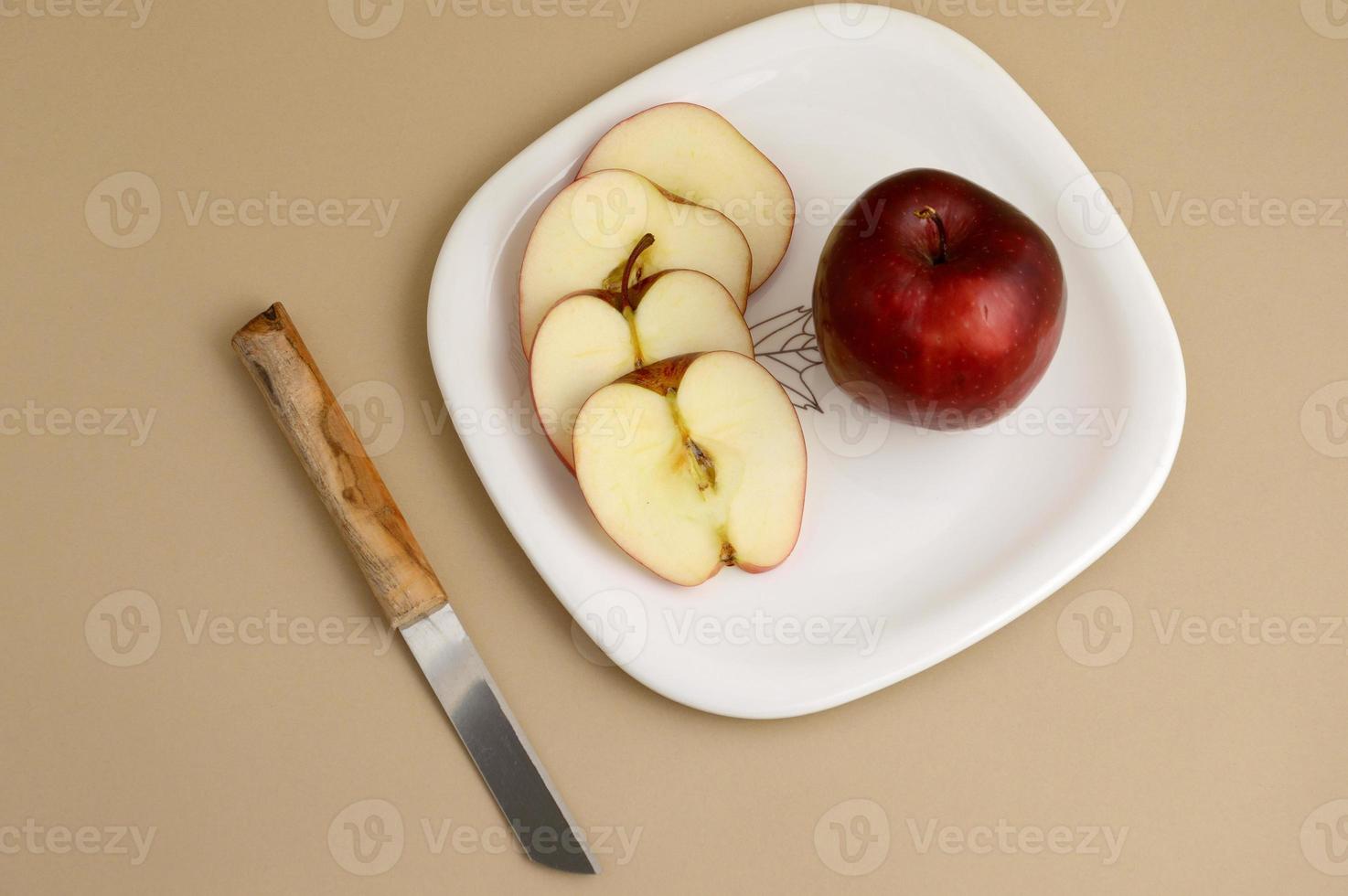 deliciosa maçã e fatia em prato branco com faca e garfo foto