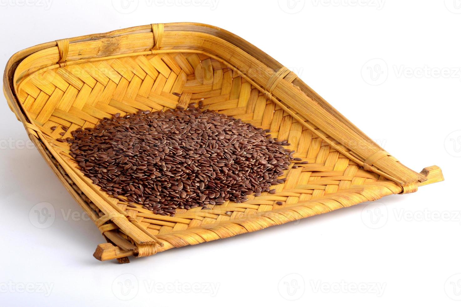 close-up de sementes de linho em uma cesta de madeira no fundo branco foto