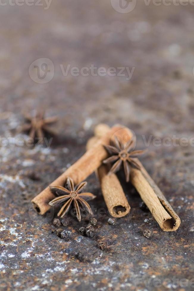 paus de canela, estrelas de anis e pimenta preta em plano de fundo texturizado foto