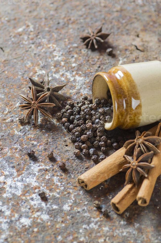 especiarias e ervas. alimentos e ingredientes da cozinha. paus de canela, estrelas de anis, pimenta preta em plano de fundo texturizado foto