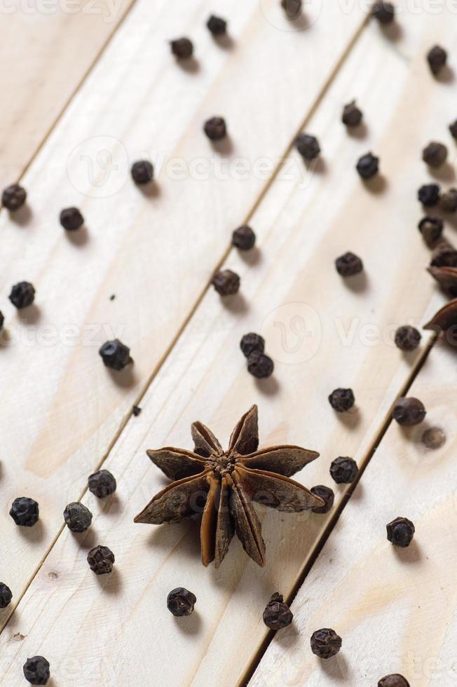 especiarias e ervas. alimentos e ingredientes da cozinha. estrelas de anis e pimenta preta em um fundo de madeira. foto