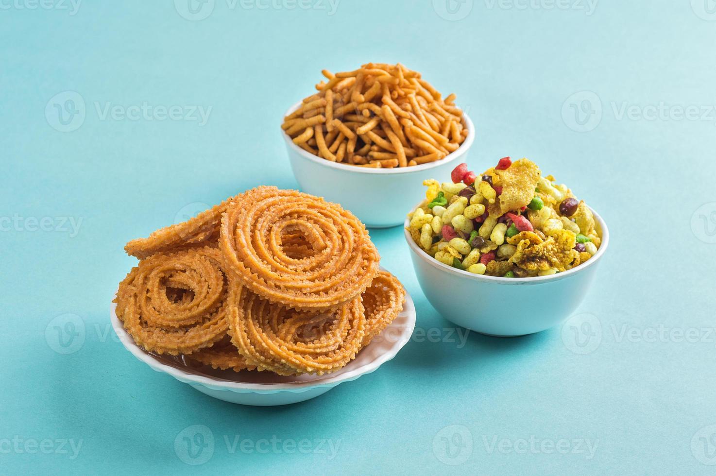 lanche indiano chakli, chakali ou murukku e besan grama farinha sev e chivada ou chiwada sobre fundo azul. comida diwali foto