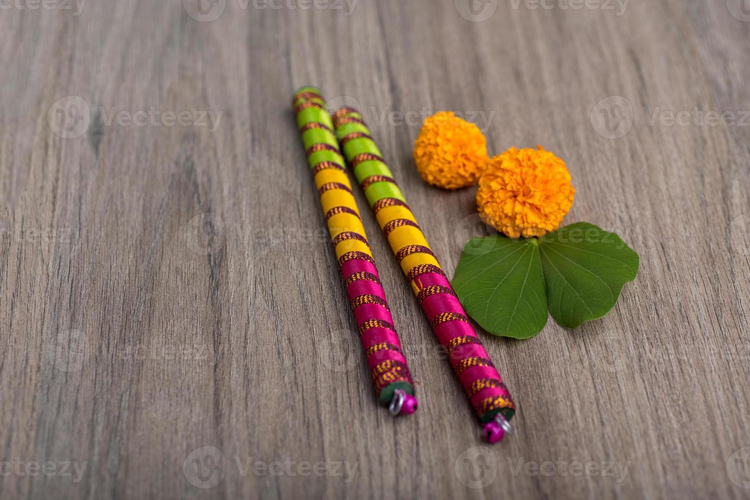 festival indiano dussehra e navratri, mostrando folhas douradas de bauhinia racemosa e flores de calêndula com paus de dandiya em um fundo de madeira foto