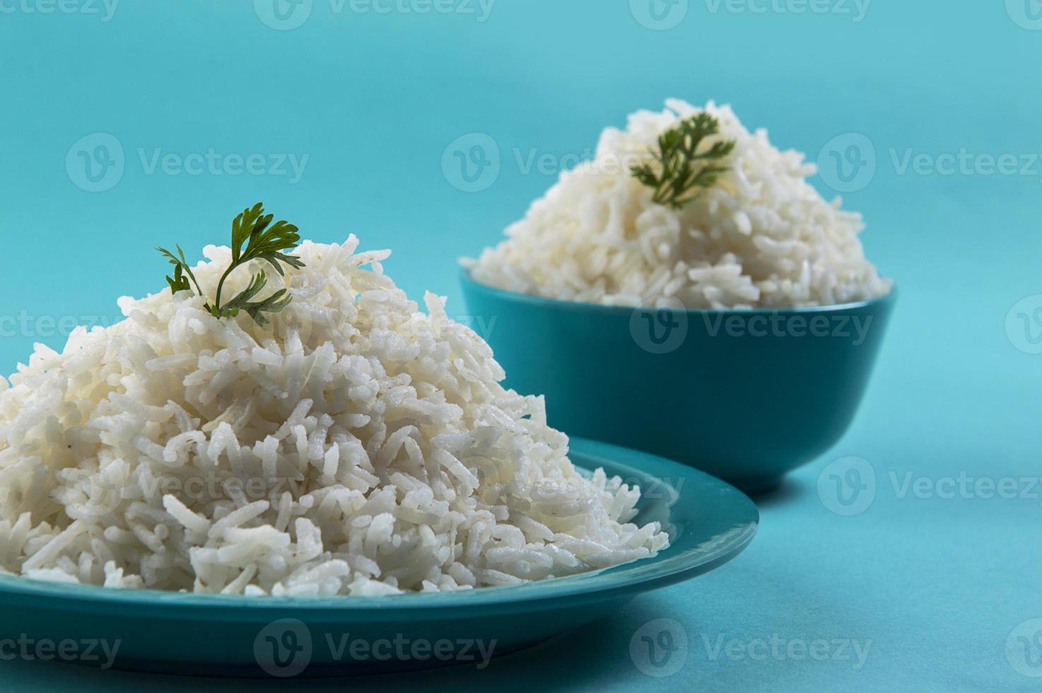 arroz basmati branco puro cozido em um prato azul e uma tigela sobre fundo azul foto