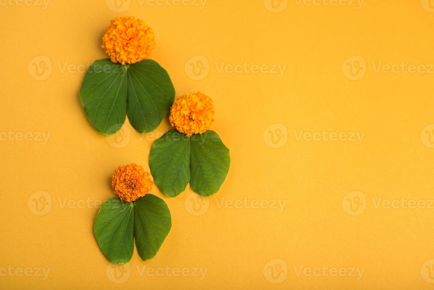festival indiano dussehra, mostrando folhas douradas bauhinia racemosa e flores de calêndula em um fundo amarelo. foto