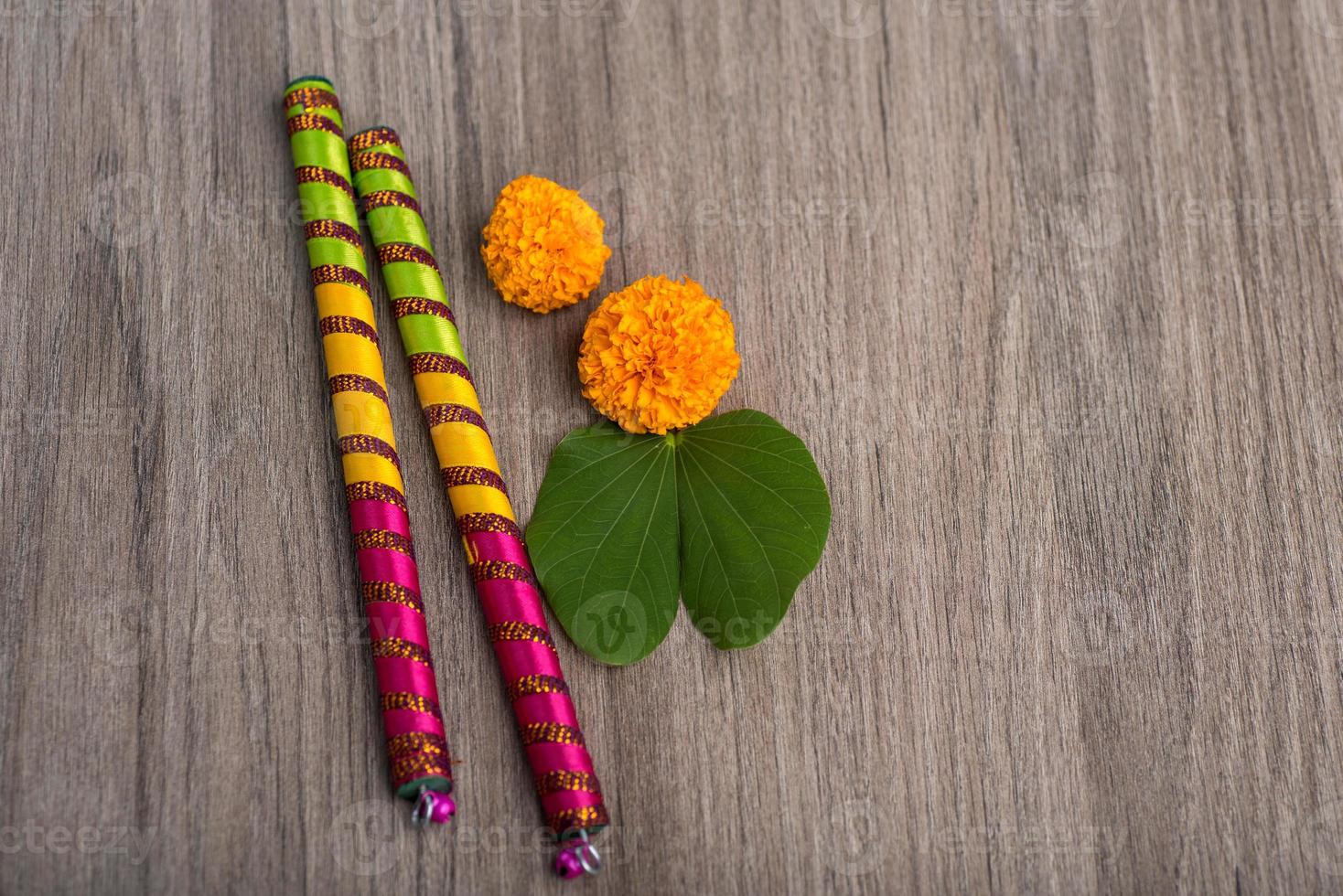 festival indiano dussehra e navratri, mostrando folhas douradas de bauhinia racemosa e flores de calêndula com paus de dandiya em um fundo de madeira foto