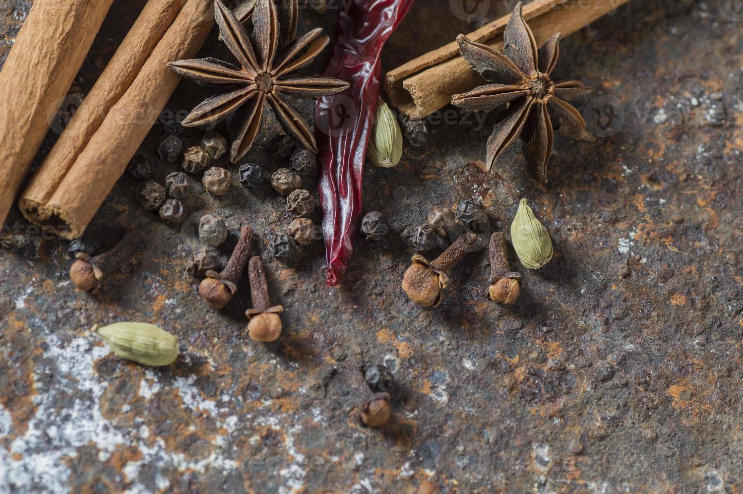 especiarias e ervas. alimentos e ingredientes da cozinha. paus de canela, estrelas de anis, pimenta preta, pimenta, cardamomo e cravo em plano de fundo texturizado foto