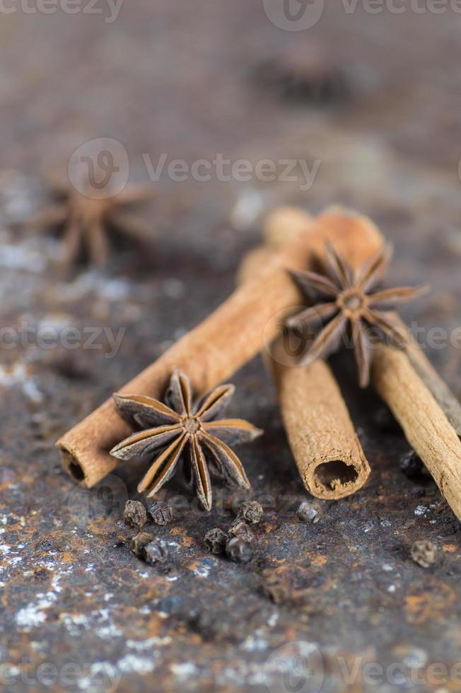 paus de canela, estrelas de anis e pimenta preta em plano de fundo texturizado foto