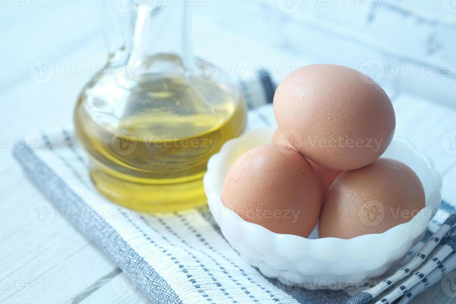 close-up de ovos em uma tigela e azeite de oliva na mesa foto