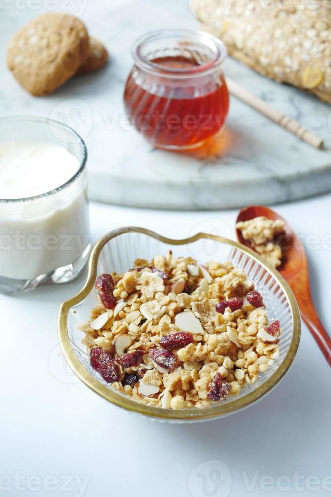 cereal matinal na tigela, mel e leite no fundo branco foto