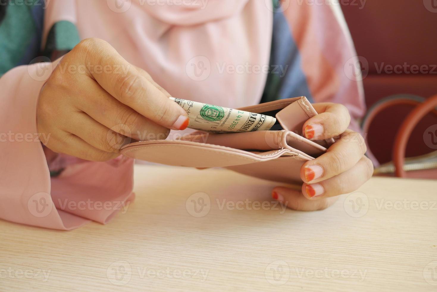 fechar a mão de uma mulher economizando dinheiro na carteira foto