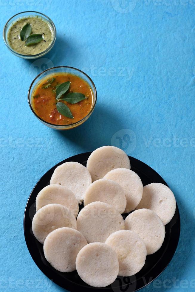 idli com sambar e chutney de coco no fundo azul, prato indiano comida favorita do sul da Índia rava idli ou semolina à toa ou rava à toa, servido com sambar e chutney de coco verde. foto