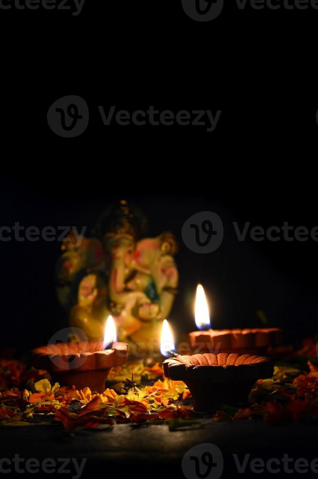 lâmpadas diya de argila acesas com o senhor ganesha durante a celebração do diwali. projeto de cartão de saudações festival indiano da luz hindu chamado diwali foto