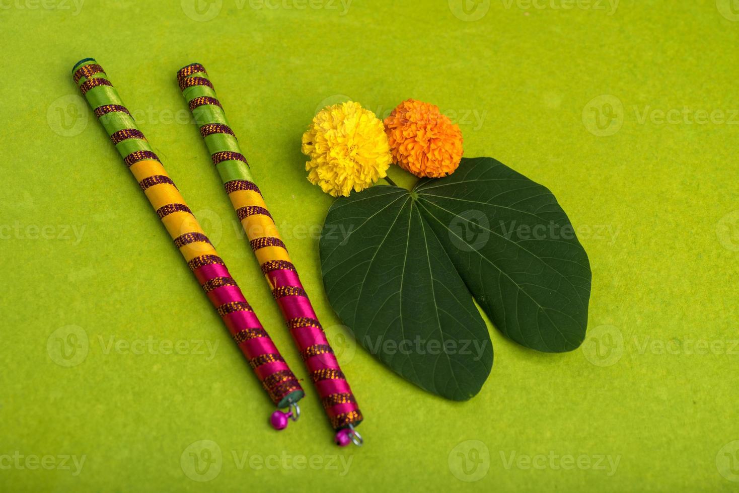 festival indiano dussehra e navratri, mostrando folhas douradas de bauhinia racemosa e flores de calêndula com paus de dandiya em um fundo verde foto