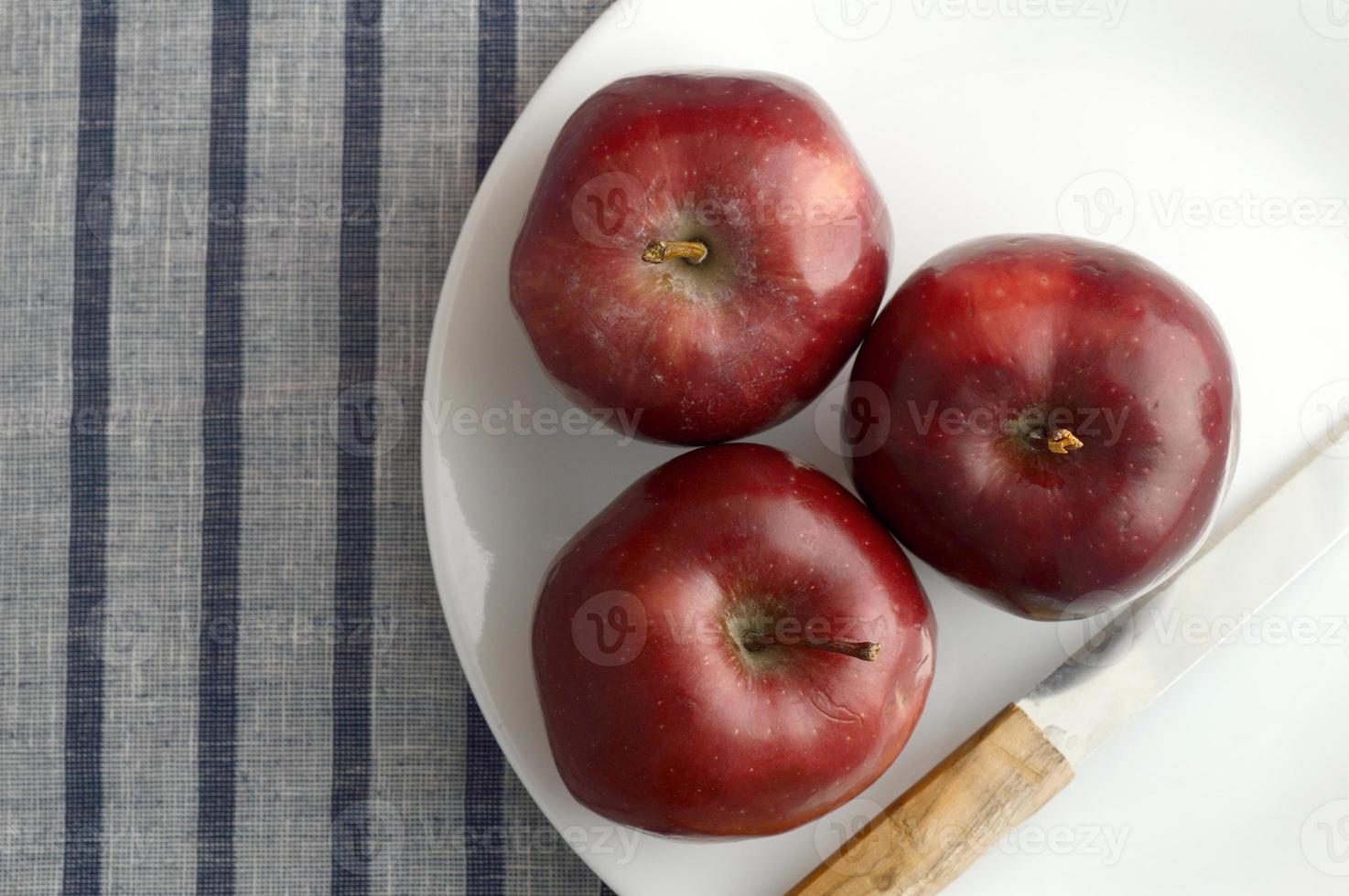 deliciosas maçãs no prato com faca na toalha de mesa listrada foto