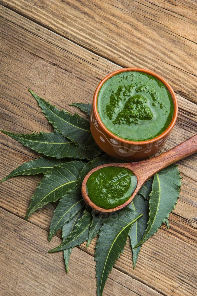 folhas de nim medicinal com pasta em fundo de madeira foto