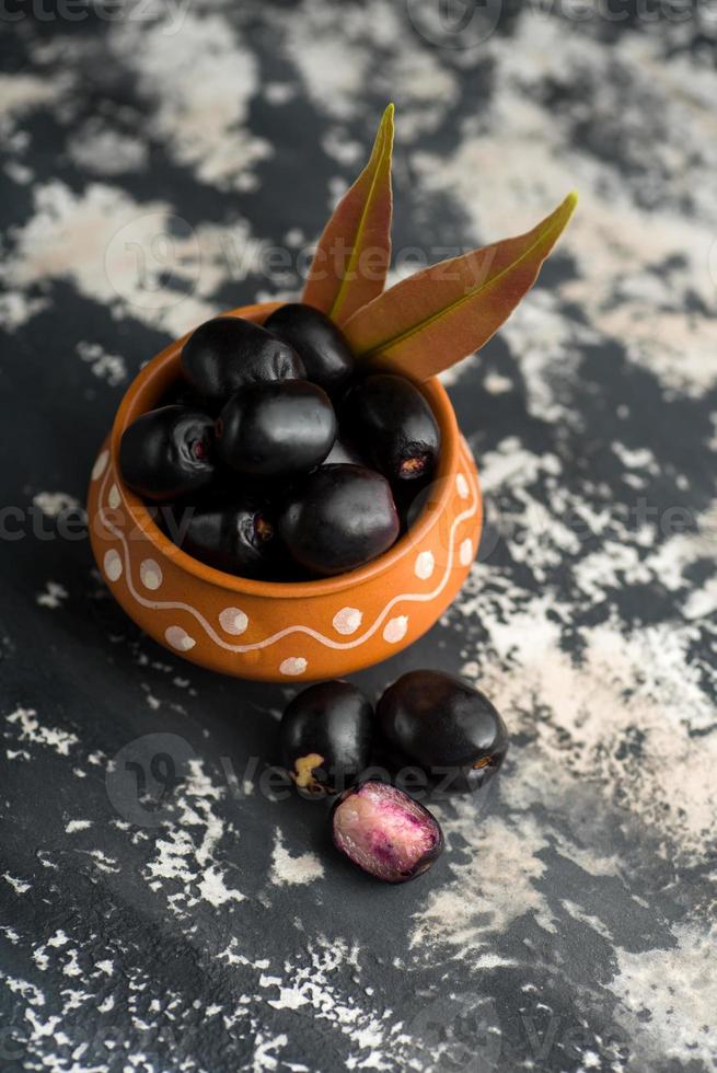 ameixa jambolan ou fruta jambul ou jamun, java ameixa syzygium cumini com folha em plano de fundo texturizado de pedra. foto