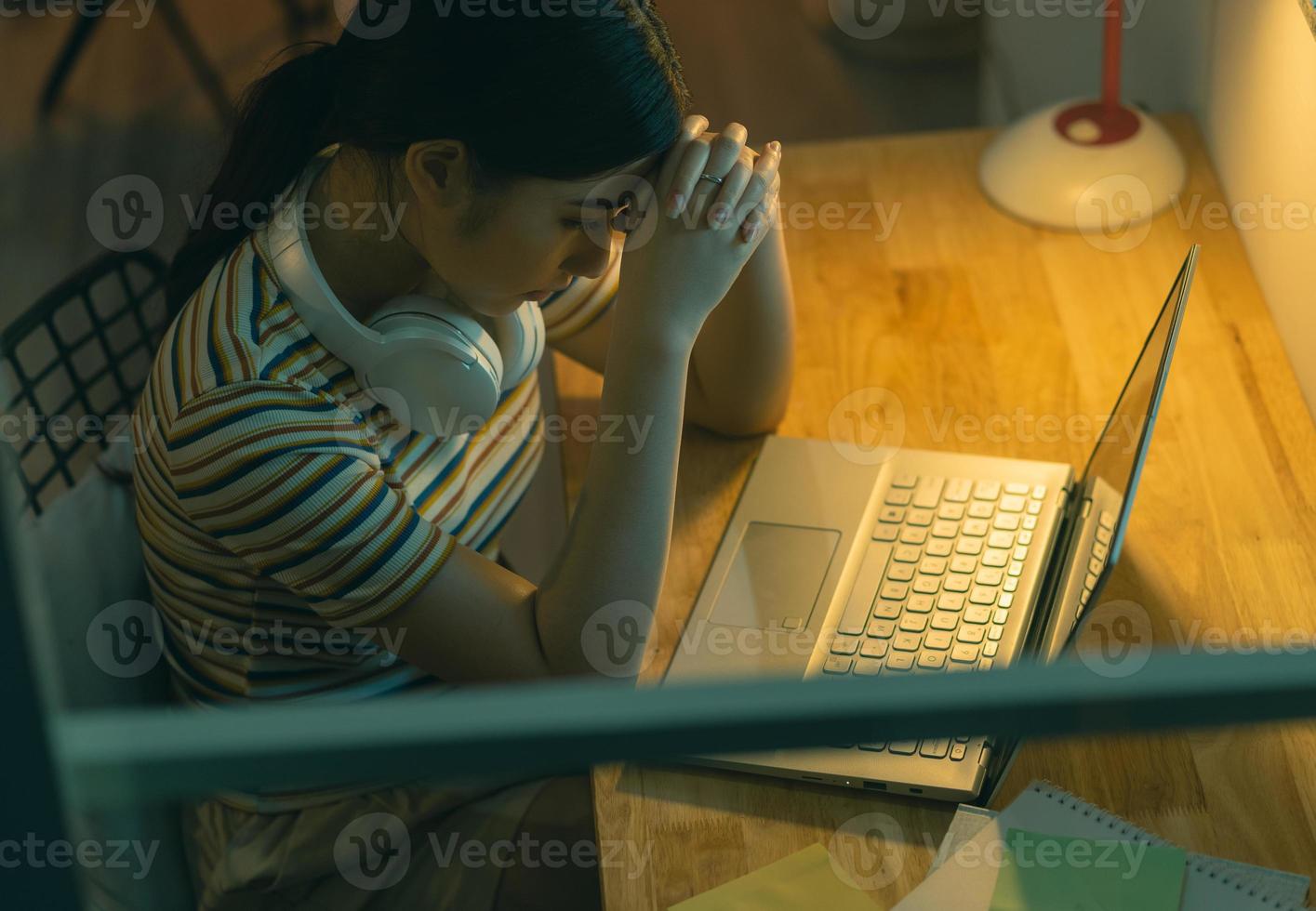 Mulher asiática cansada tentando trabalhar à noite foto