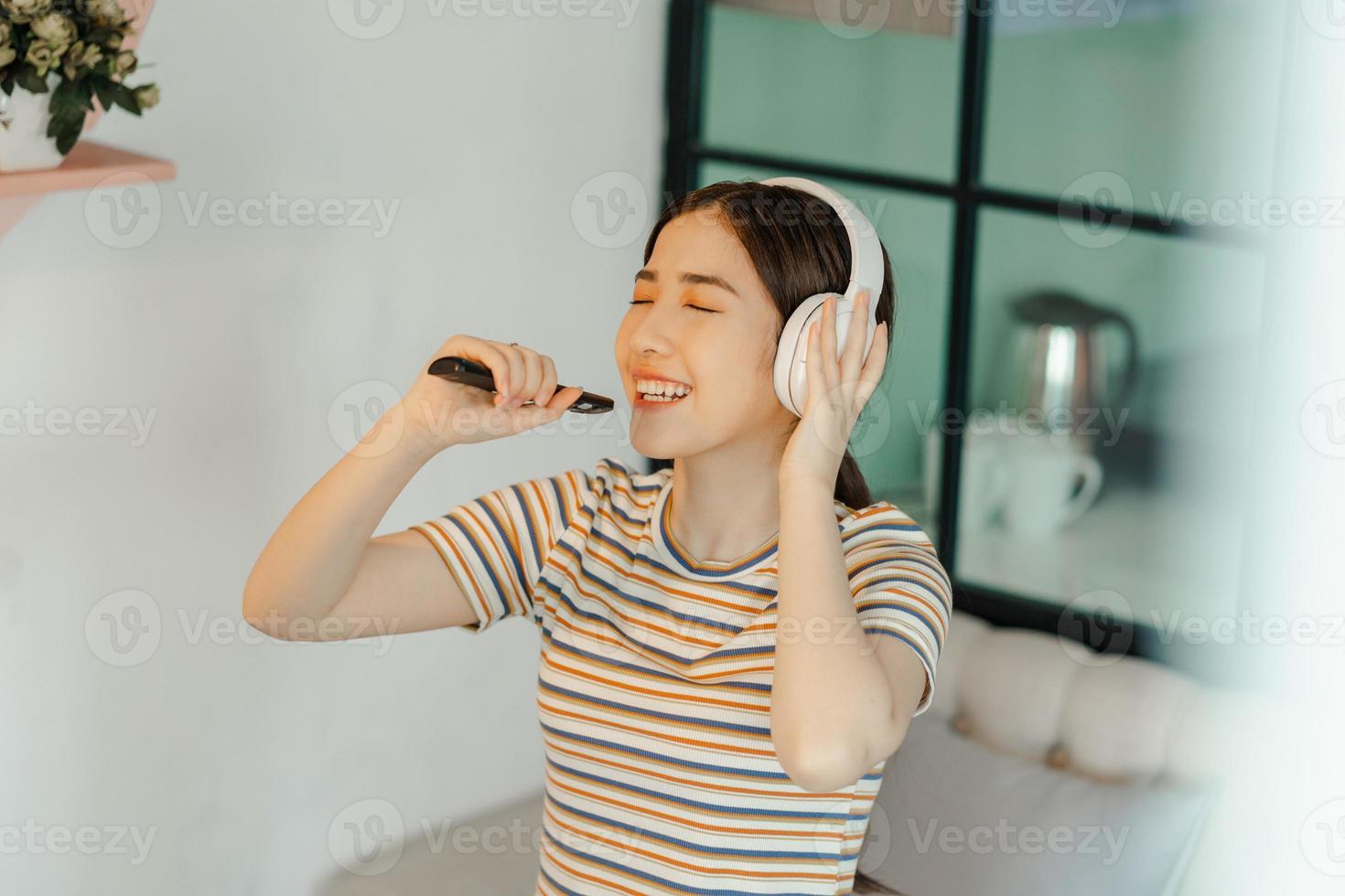 linda mulher asiática cantando na sala de estar foto