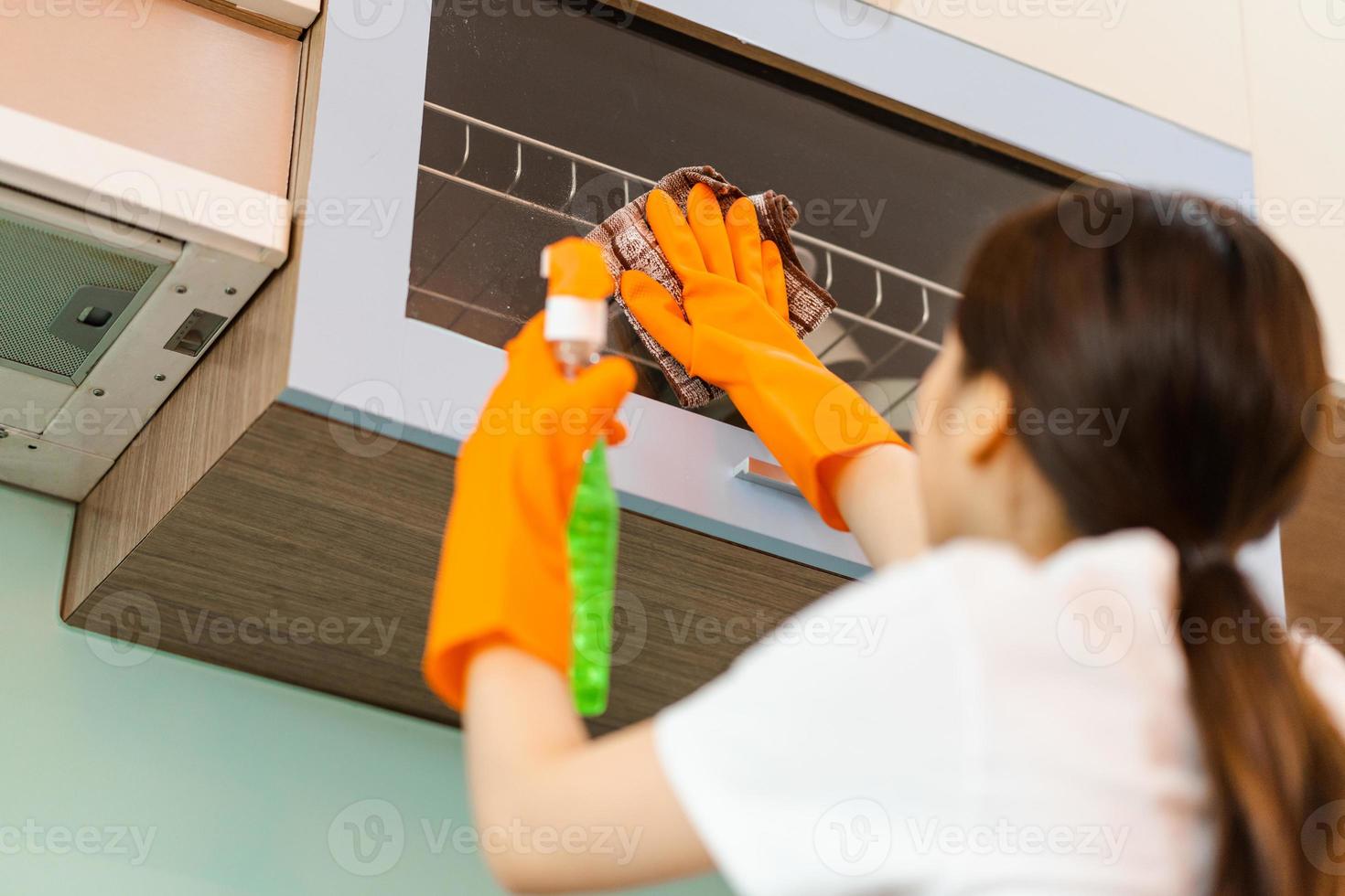 linda mulher asiática limpando armários de cozinha foto