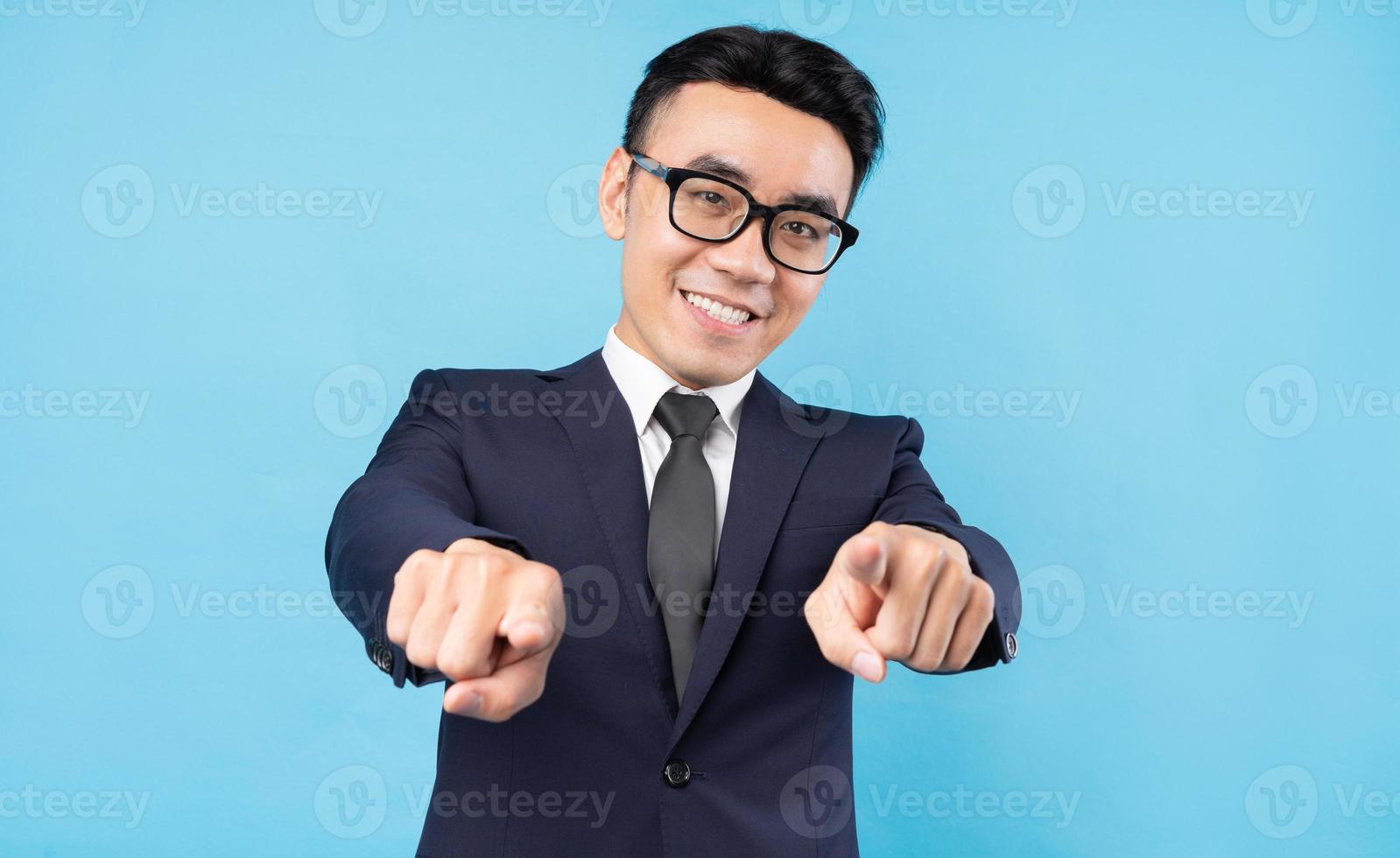 Buisnessman asiático vestindo terno apontando sobre fundo azul foto