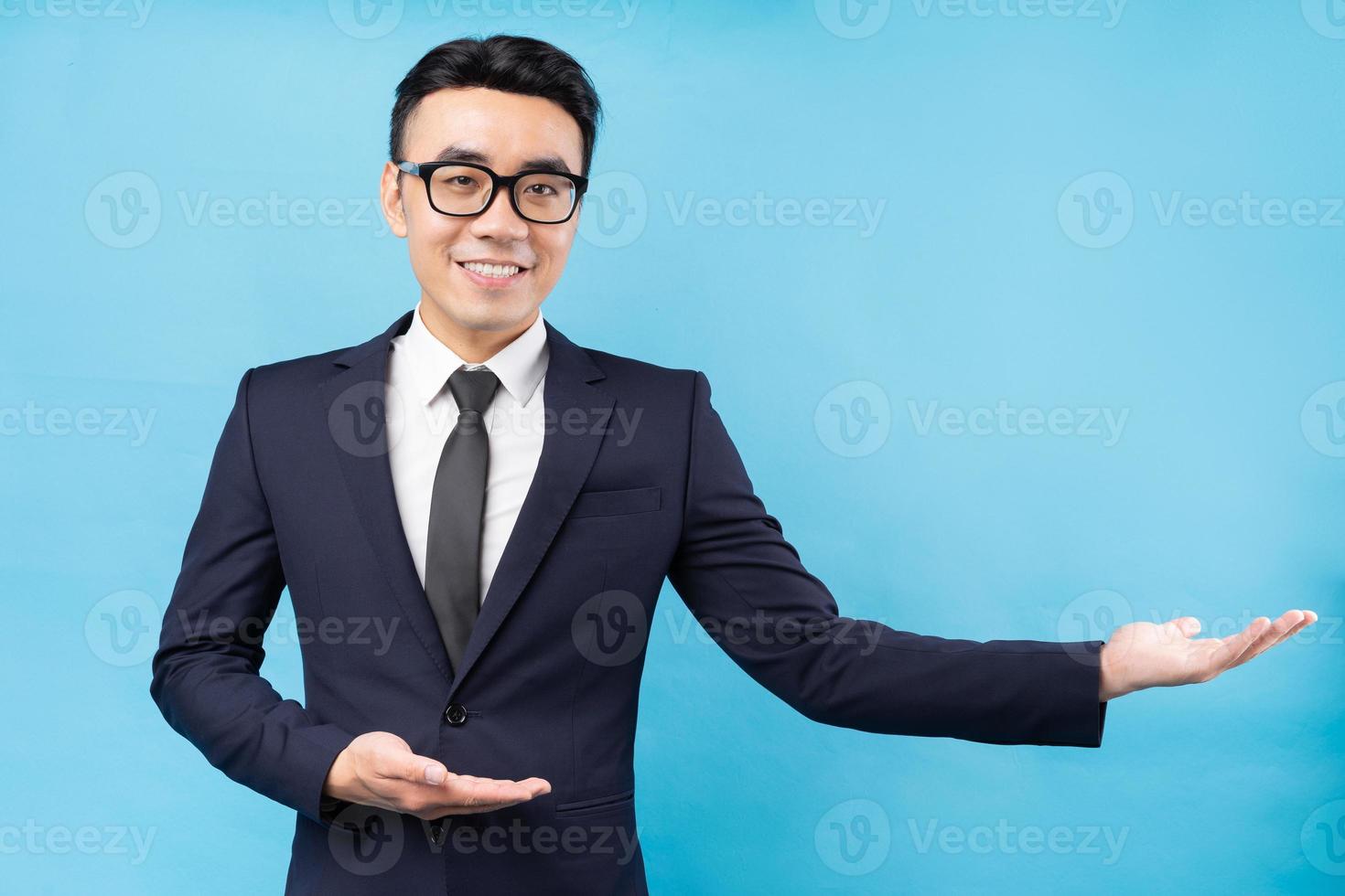 retrato de empresário asiático vestindo terno sobre fundo azul foto