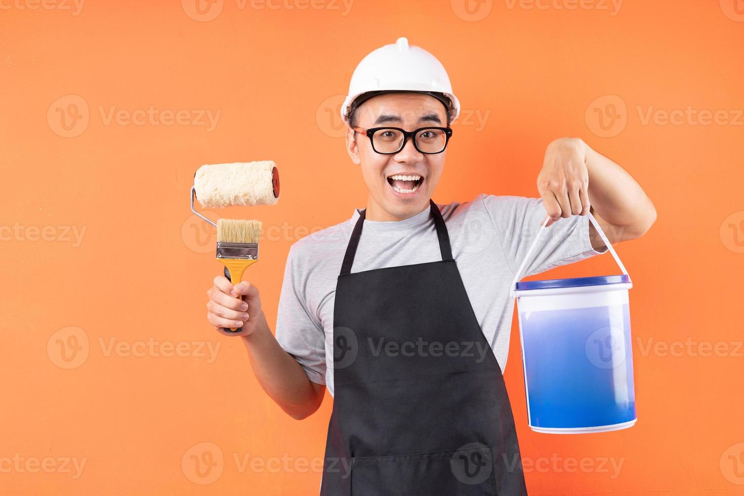 pintor asiático segurando pincel e posando em fundo laranja foto