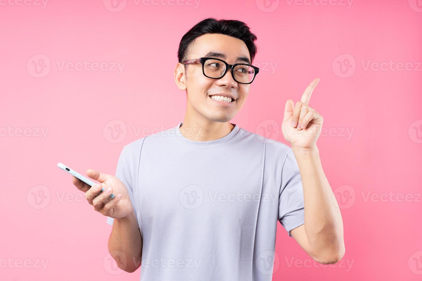 retrato de homem asiático usando smartphone em fundo rosa foto