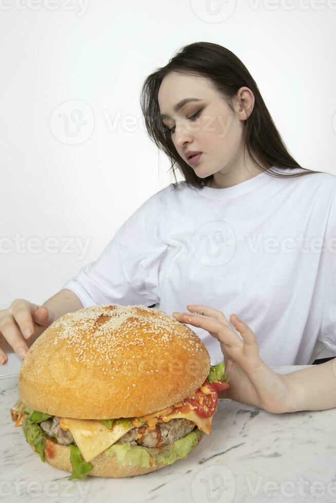 uma mulher é segurando uma grande churrasco Hamburger sanduíche em a fundo. velozes Comida conceito. a menina tem uma enorme Hamburger. foto