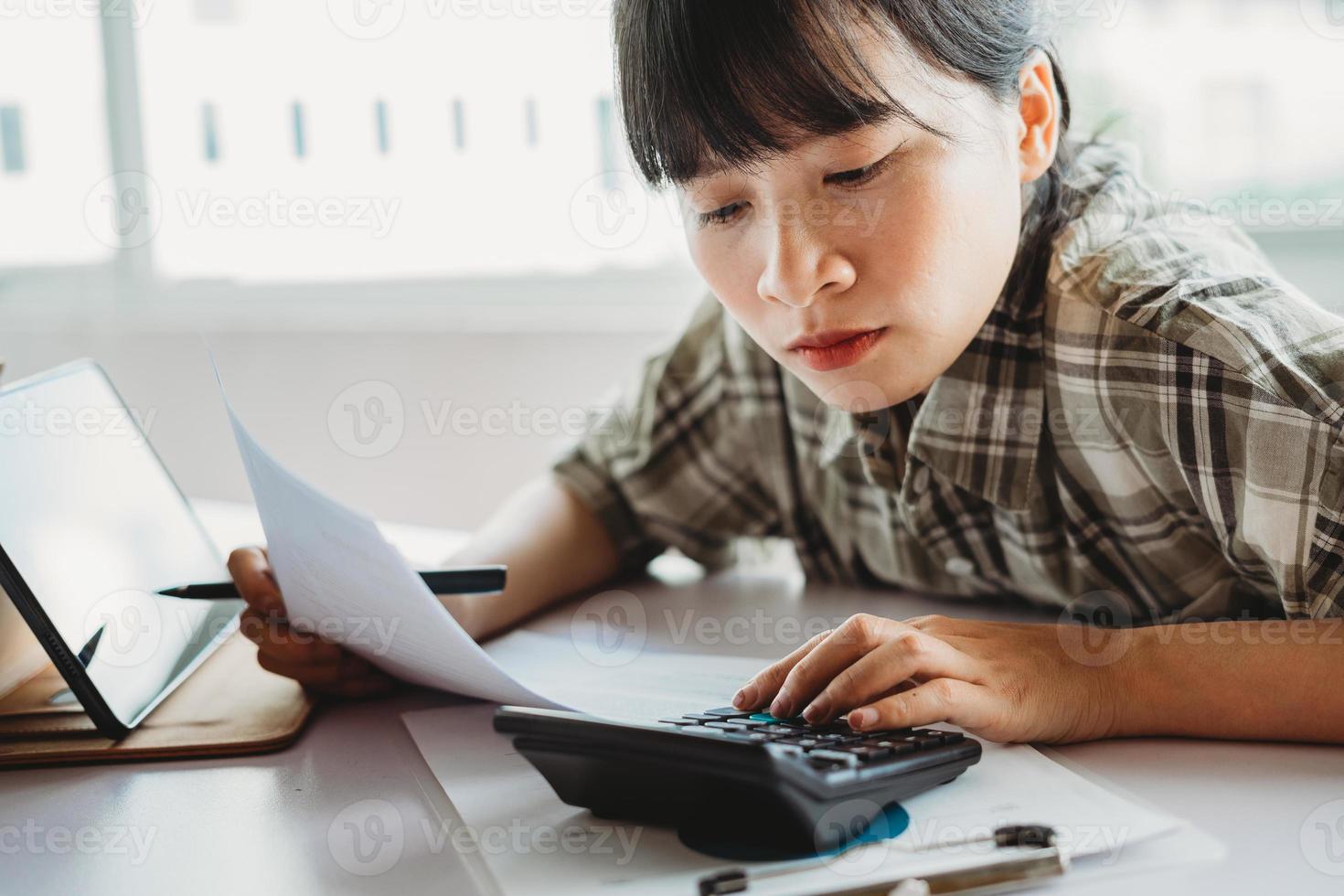 jovem mulher asiática está calculando o imposto a pagar foto