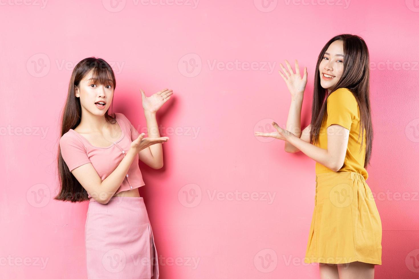 retrato de duas lindas garotas asiáticas posando em fundo rosa foto