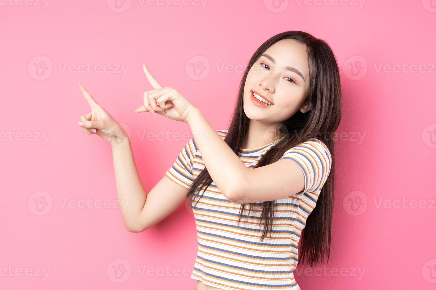 jovem mulher asiática posando em fundo rosa foto