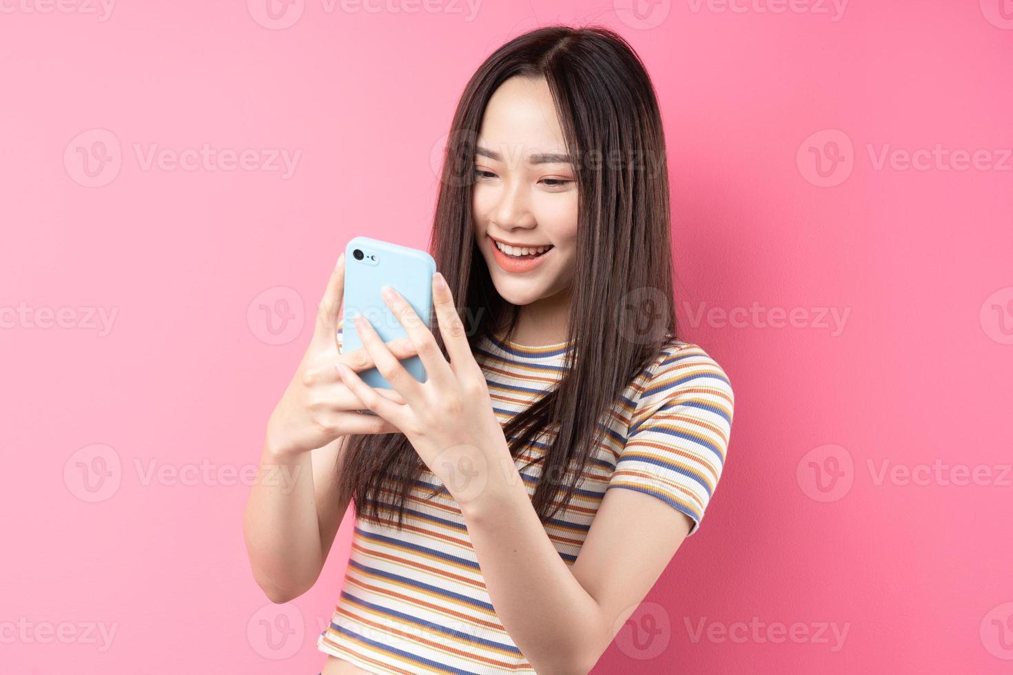 jovem mulher asiática usando smartphone em fundo rosa foto