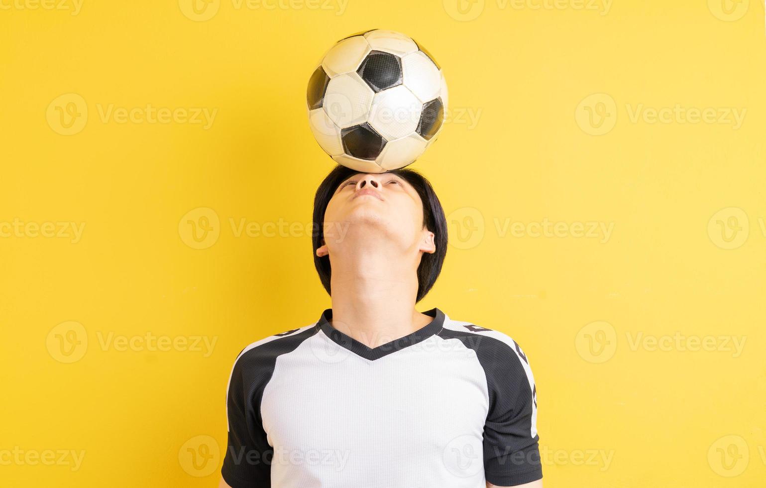 o homem asiático está quicando a bola com a cabeça foto