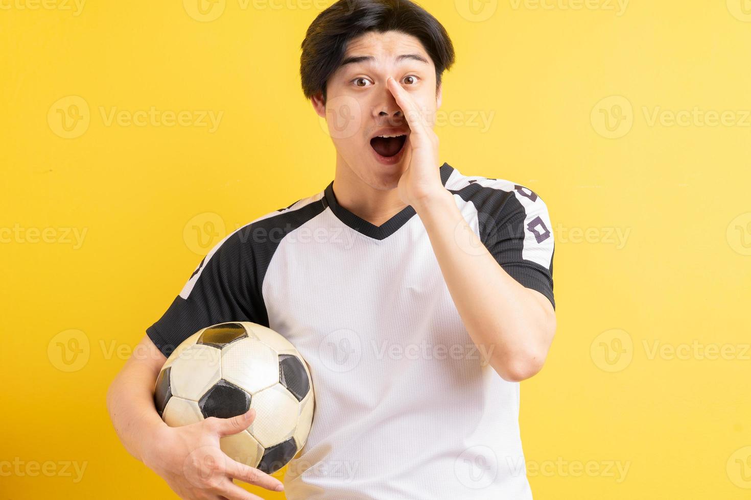 o homem asiático segurando a bola e gritando foto