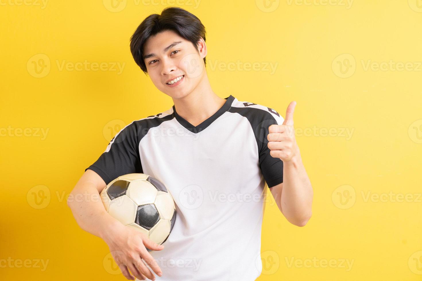 o homem asiático está segurando a bola e levantando os polegares foto