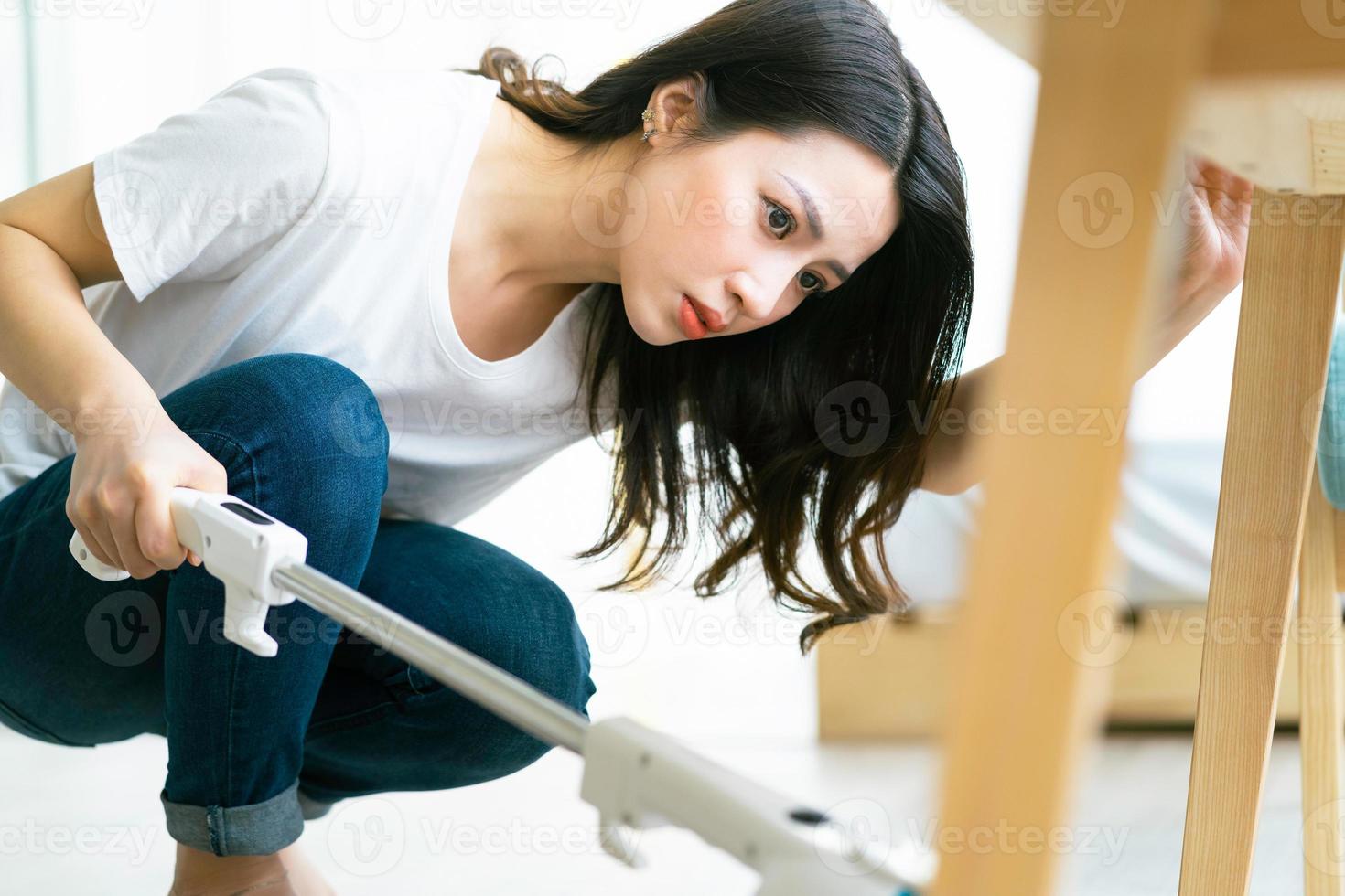 mulher asiática limpando o chão com um aspirador de pó foto