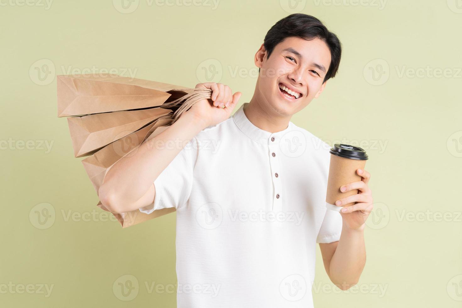 um bonito empresário asiático segurando sacolas de compras e uma xícara de café para levar foto