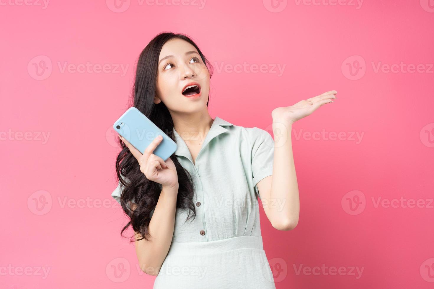 jovem asiática segurando um telefone e olhando para cima com entusiasmo foto