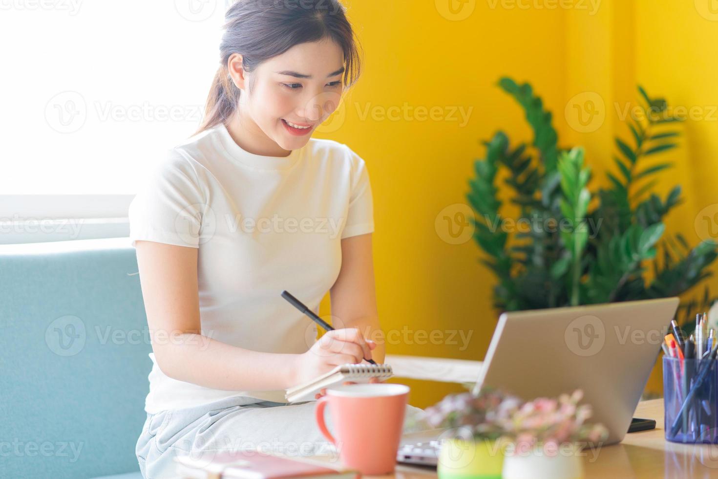 jovem mulher asiática sentada no sofá trabalhando em casa foto