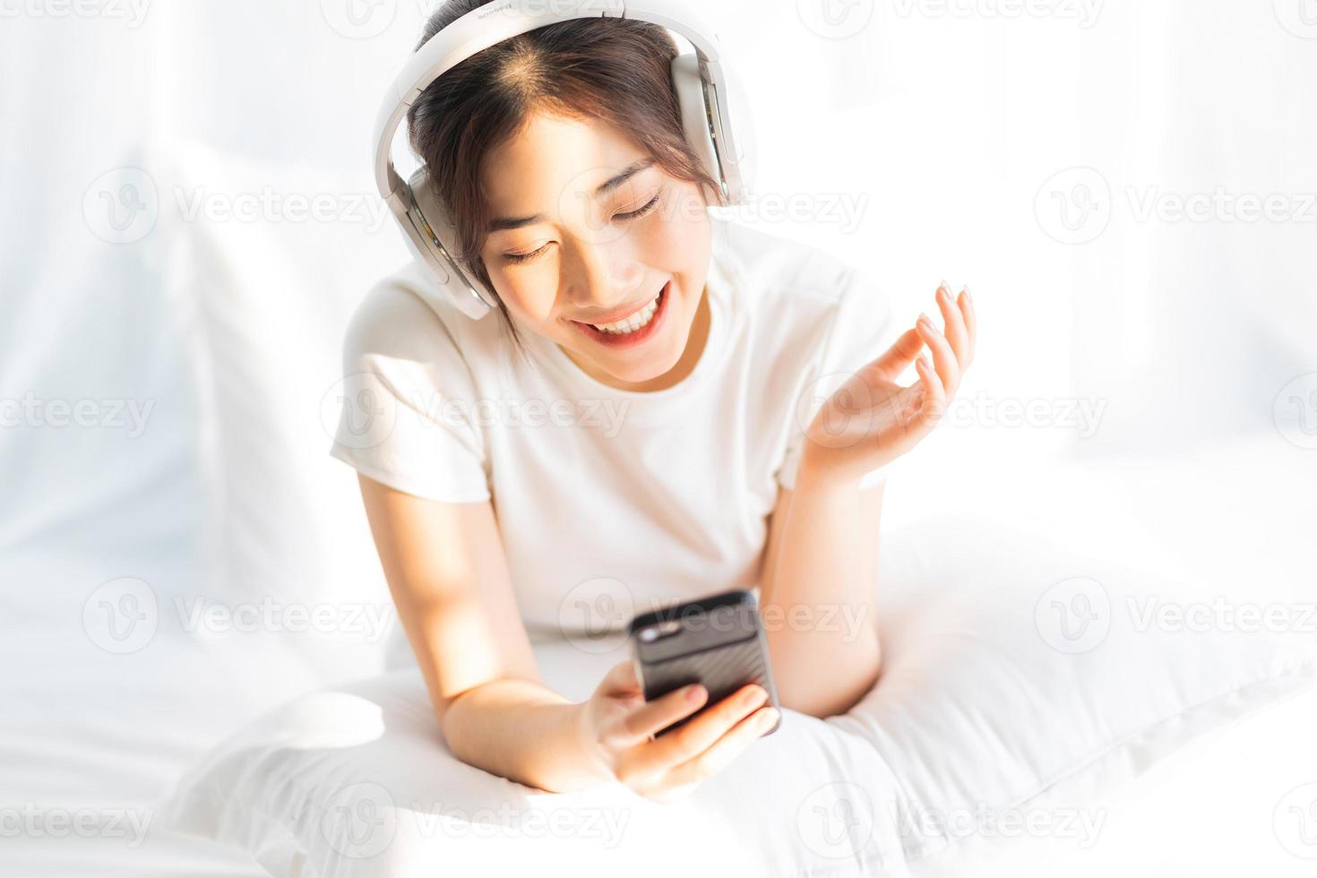 jovem sentada na cama ouvindo música divertida foto